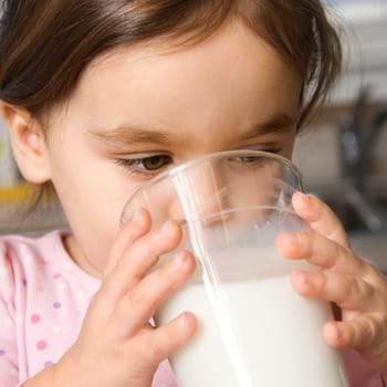 Caucasian girl drinking glass of milk.