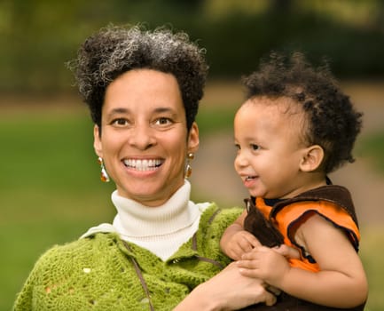 Head and shoulder portrait of woman holding boy and smiling.