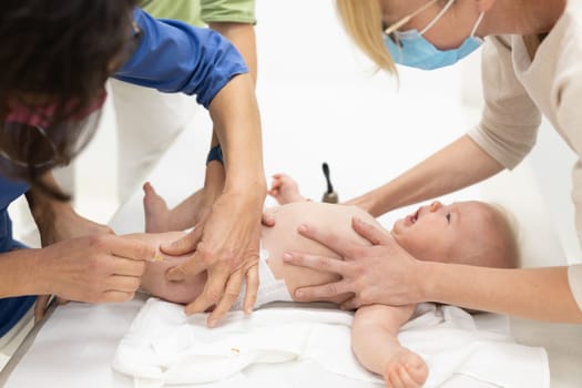 Baby beeing vaccinated by pediatrician in presence of his mother. Preventive vaccination against Diphtheria, whooping cough, tetanus, hepatitis, haemophilus influenzae, pneumococcus, poliomyelitis.