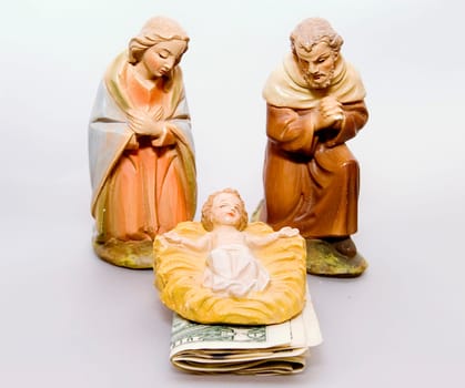 Commercialism vs Christmas, Mary and Joseph looking at baby Jesus, with money under the manger.