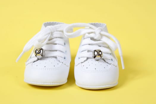 Little Baby shoes together on yellow background