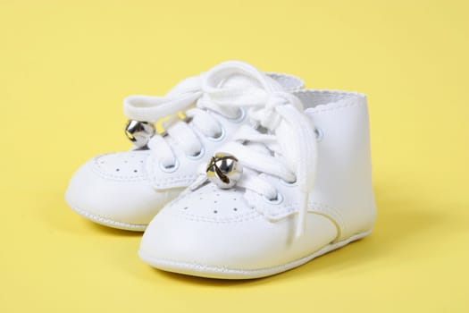 Small Baby shoes together on yellow background