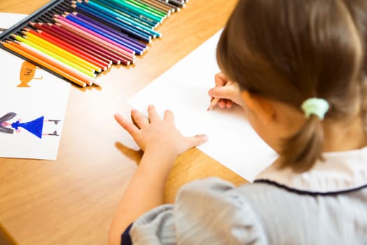 little girl playing with colors. The focus is on the hand drawing