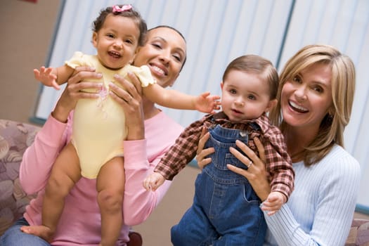 Two mothers holding baby boy and girl looking to camera
