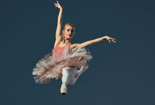 Beautiful female ballet dancer on a grey background. Ballerina is wearing  pink tutu and pointe shoes