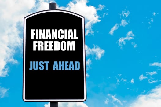 FINANCIAL FREEDOM JUST AHEAD  motivational quote written on road sign isolated over clear blue sky background with available copy space. Concept  image