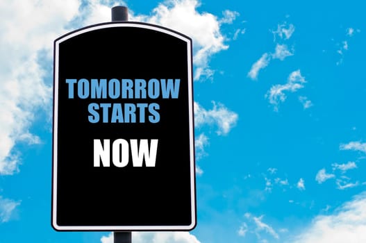 TOMORROW STARTS NOW motivational quote written on road sign isolated over clear blue sky background with available copy space. Concept  image