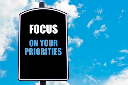FOCUS ON YOUR PRIORITIES  motivational quote written on road sign isolated over clear blue sky background with available copy space. Concept  image