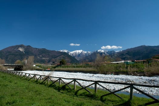 view of a portion of the fence and the river with a backdrop of the Apuan Alps