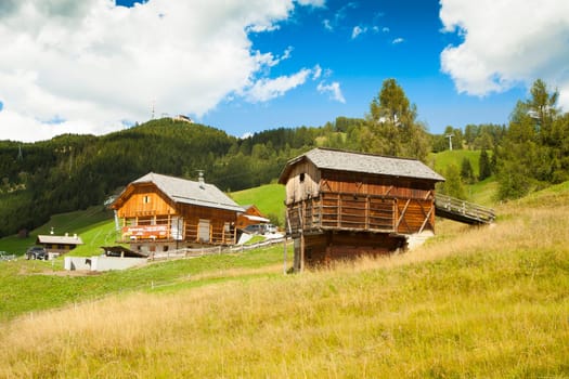 A refuge and a restaurant in nearby high Badia on green grass with blue sky and white clouds