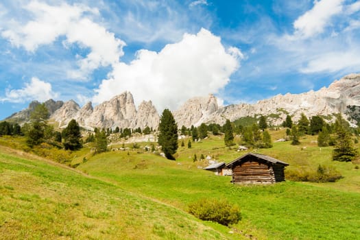 View of a landscape of high mountain with green grass and an isolated cabin