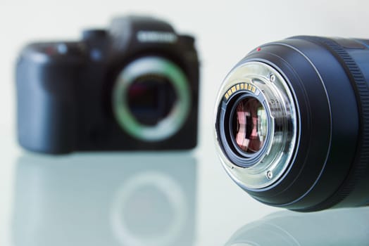 Still life of dslr camera and photo lens on glass table. Closeup of electronic circuit, rear glass and mount with copyspace in foreground