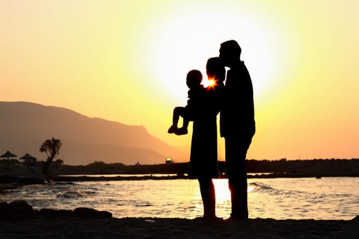 silhouette of a happy family of three on the beach