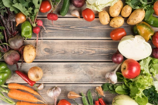 Colorful mix of fresh farm vegetables and fruits, top view. Table full of organic ripe seasonal harvest. Nitrate free food or healthy diet concept. Objects circular arrangement. Cooking ingredients.