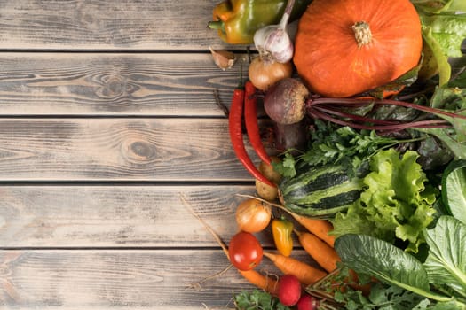 Colorful mix of fresh vegetables, top view. Sorting of organic seasonal harvest on wooden table. Nitrate free food or healthy diet concept. Balanced nutrition. Cooking ingredients. Place for text.