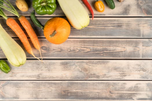 Row of fresh farm vegetables on wooden table, top view. Seasonal foodstuffs composition. Nitrate free food or healthy diet concept. Objects layout. Planking. Cooking ingredients. Place for text.