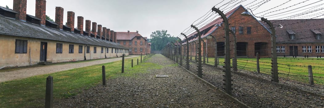 Barracks for prisoners behind barbed wire fence in Auschwitz Nazi concentration camp Poland