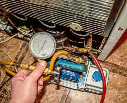 Vacuum pump of the refrigeration unit during repair. Refrigerator repair. Vacuum pump. Pressure gauge. Refrigeration unit motor. Service maintenance. Household appliances repair workshop.
