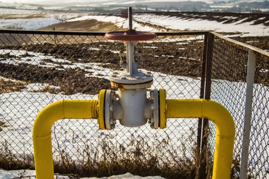 Gas pipe with valve for opening and closing the supply. Natural gas pipeline. Adjustment valve. North. White snow in winter. Flow. Industrial equipment. European consumer.