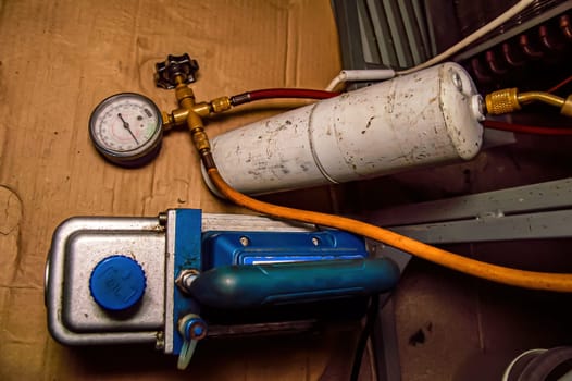 Vacuum station for filling the refrigerator with refrigerant. Refrigerator repair. Gas cylinder. Vacuum pump. Manometer for checking the gas pressure in the refrigerator system. Service workshop.