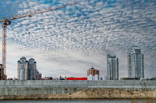 Mounting high-rise crane at a construction site. Building bussiness. High-rise residential buildings. Crane for lifting building materials. Construction and repair. Area of new buildings.