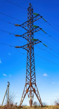 Tower with high-voltage wires for power transmission. Electrical cables on a metal tower. High voltage electric line. Blue sky. Energy business. Energy business. Eeology.