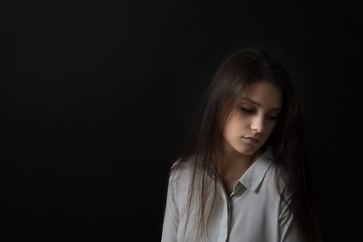 Low key studio portrait of sad girl. Horizontally.