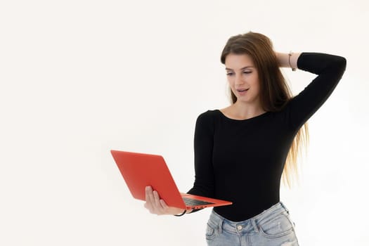 Surprised charming young woman holding laptop in hand. Isolated on white background.