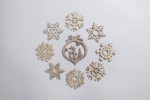 Christmas winter festive ornament. Christmas snowflakes and wooden decoration on white background. Christmas holiday decoration. Minimal holiday greeting season. Flat lay, top view.