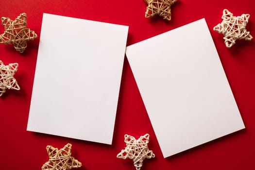 Christmas winter festive ornament. Blank paper cards with wooden decoration on red background. Minimal decoration. Invitation Christmas holiday party. Flat lay, top view, copy space.