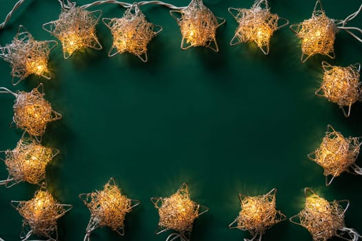 Christmas winter festive ornament. Christmas lights frame on green background. Invitation Christmas holiday party. Flat lay, top view, copy space.