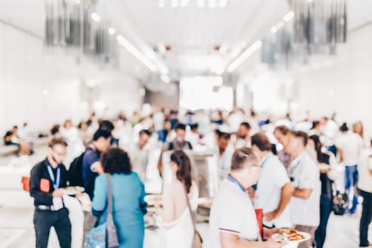 Abstract blurred people socializing during buffet lunch break at business meeting or conference.