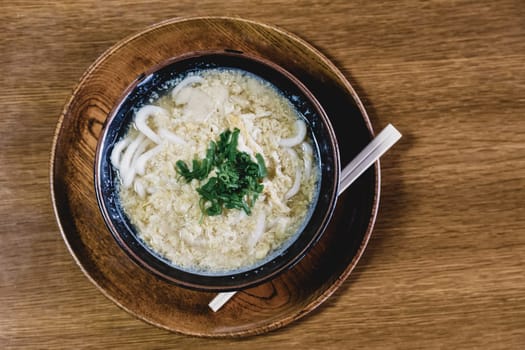 Miso Ramen Asian noodles with egg and parsley in wooden bowl on brown rustic background.