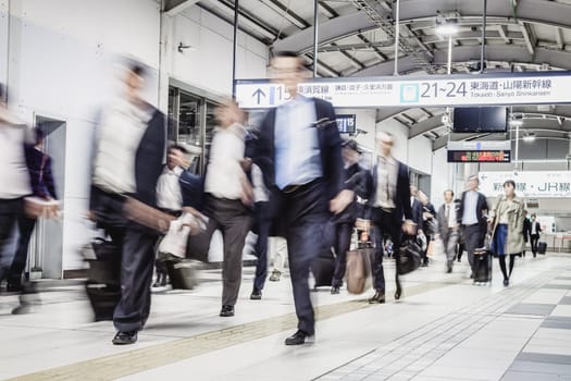 Corporate business people commuting to work by Tokyo public transport. Unrecognizable people blured in motion while rushing to train platforms.