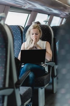 Businesswoman sitting and traveling by train working on laptop.
