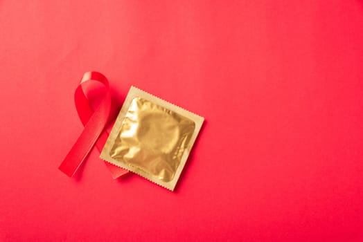 Red bow ribbon symbol HIV, AIDS cancer awareness and condom with shadows, studio shot isolated on red background, Healthcare medicine sexually concept, World AIDS Day