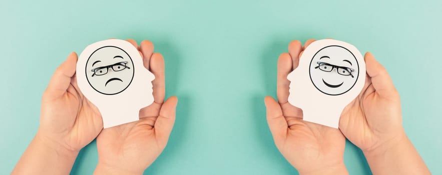 Holding a head with a sad and a happy face in the hands, mental health concept, positive and negative mindset, depression, support and evaluation symbol, emotion