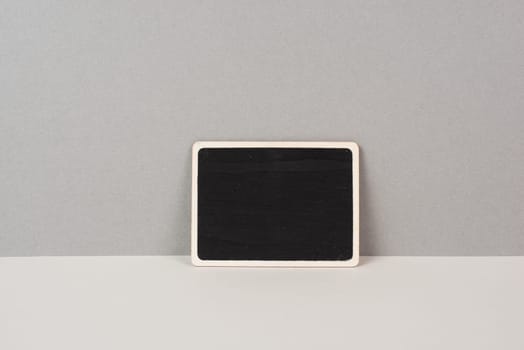 Black chalkboard sign on a gray background, copy space for text, minimalism