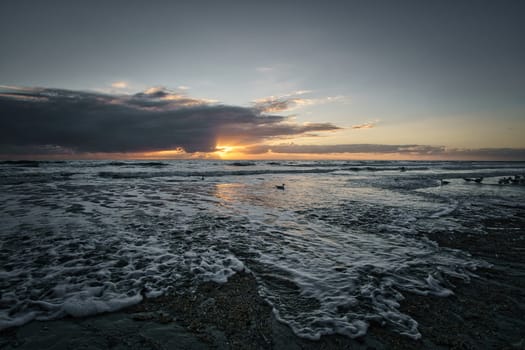 Sunset on the beach in Denmark. Waves on the sand. Walk on the coast in the sand. Landscape photo by the sea