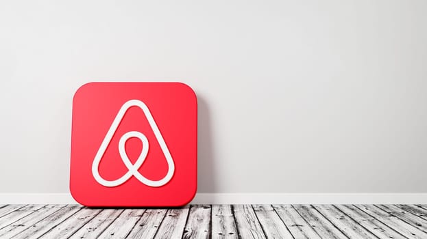 Airbnb App Icon 3D Symbol Shape on Wooden Floor Against Gray Wall with Copy Space 3D Render Illustration