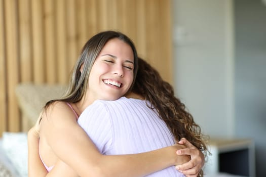 Happy friends hugging on a bed in a room