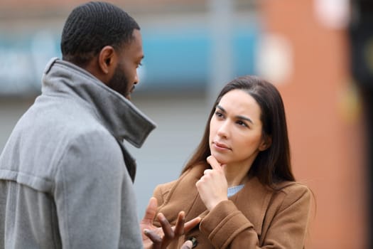 Attentive woman listening a man talking in winter in the street