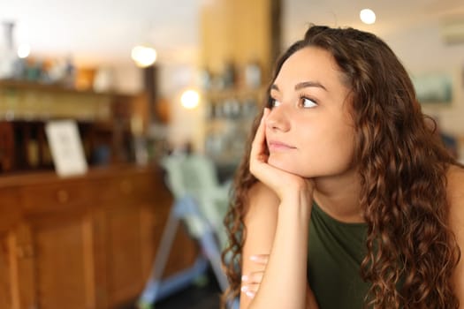 Distracted and pensive woman looking away in a restaurant