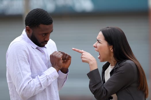 Furious woman scolding to a black man in the street