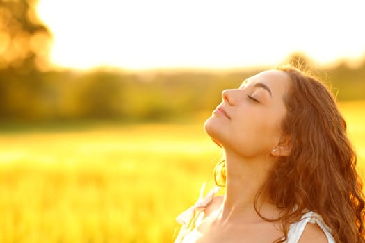 Relaxed woman breathing fresh air in a rural environment at sunset