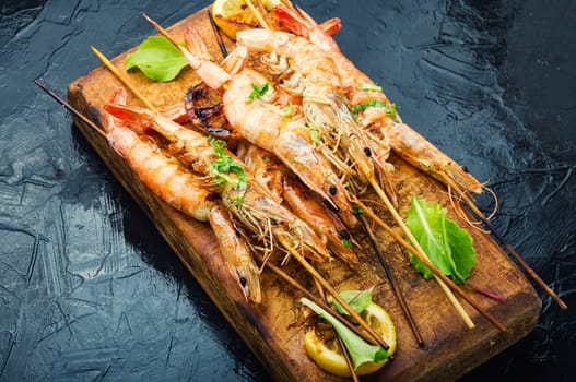 Delicious prepared grilled shrimp on skewers. Shrimps served on a cutting board
