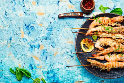 Delicious prepared grilled shrimp on skewers. Shrimps served on a cutting board