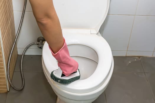 Woman cleaning toilet ware that is very dirty.