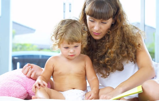 High key portrait  of young mother reading a book for her baby