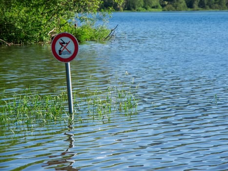 Blick auf ein vom Hochwasser im Grüntensee umgebenes Verkehrszeichen nahe dem Seeufer mit der Bedeutung nicht in das Wasser Springen.